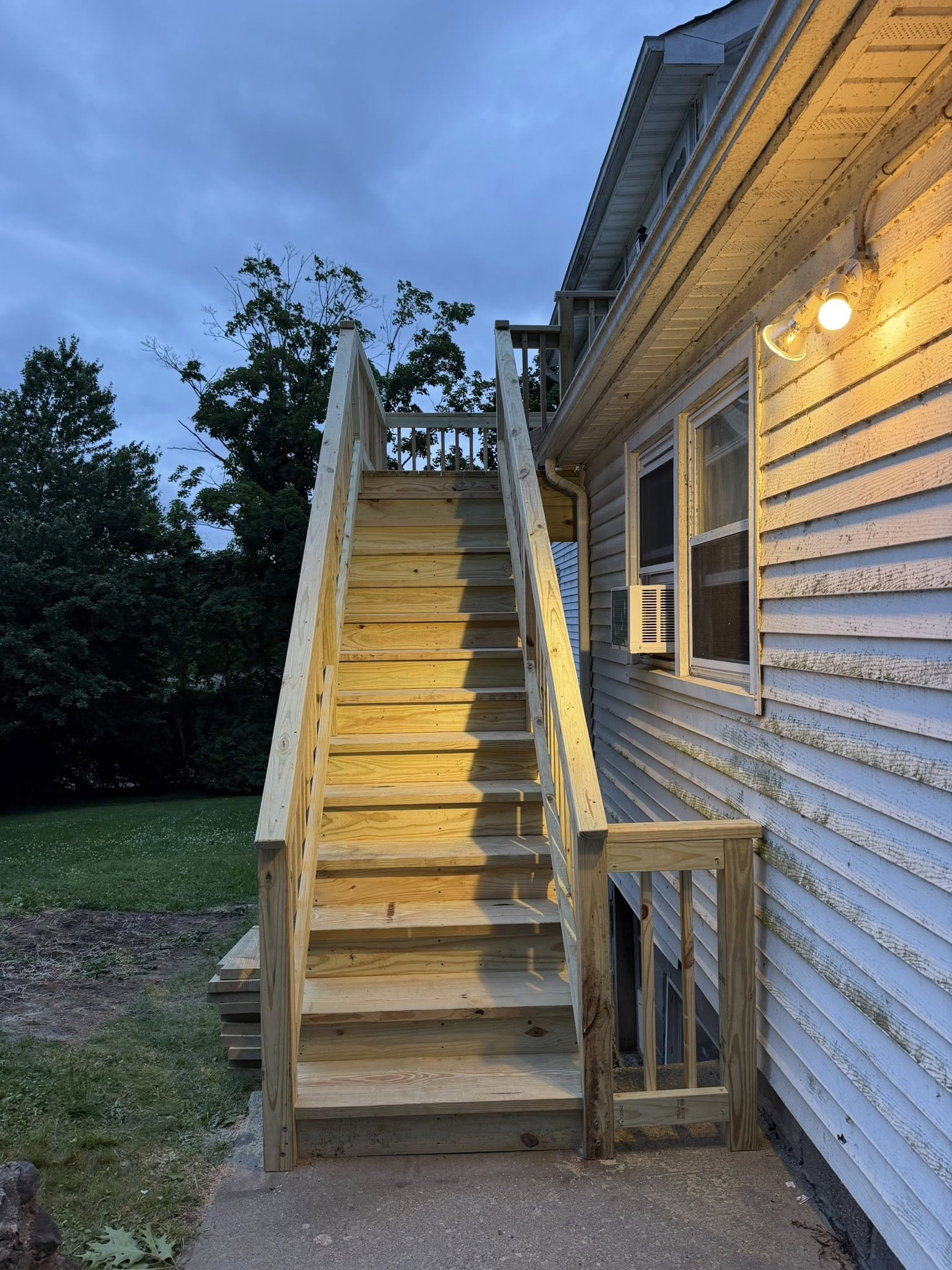New exterior staircase lit at dusk — pressure treated lumber Westchester NY